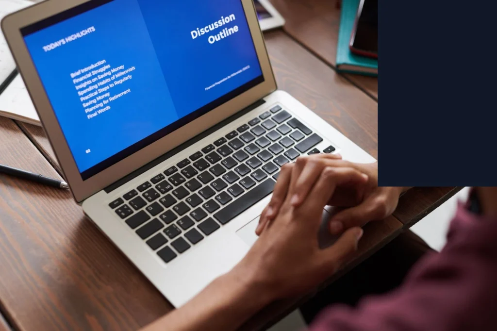 Laptop ekranında mavi renkli bir sunum/yazı belgesi gösteriliyor ve kişi klavyede yazı yazıyor. Web tarayıcıda açık görünen bir uygulama/sunum aracı var.