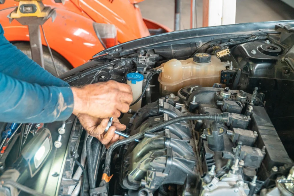 Açık motor kaputu içinde hidrolik direksiyon yağı haznesini (mavi kapakla) ve seviye kontrolünü yapan bir kişinin eli görülmektedir.