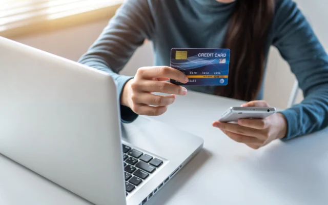 Telefonla online alışveriş yapan kişi, elinde kredi kartı
