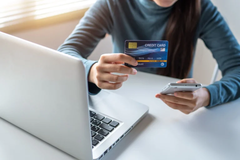 Telefonla online alışveriş yapan kişi, elinde kredi kartı
